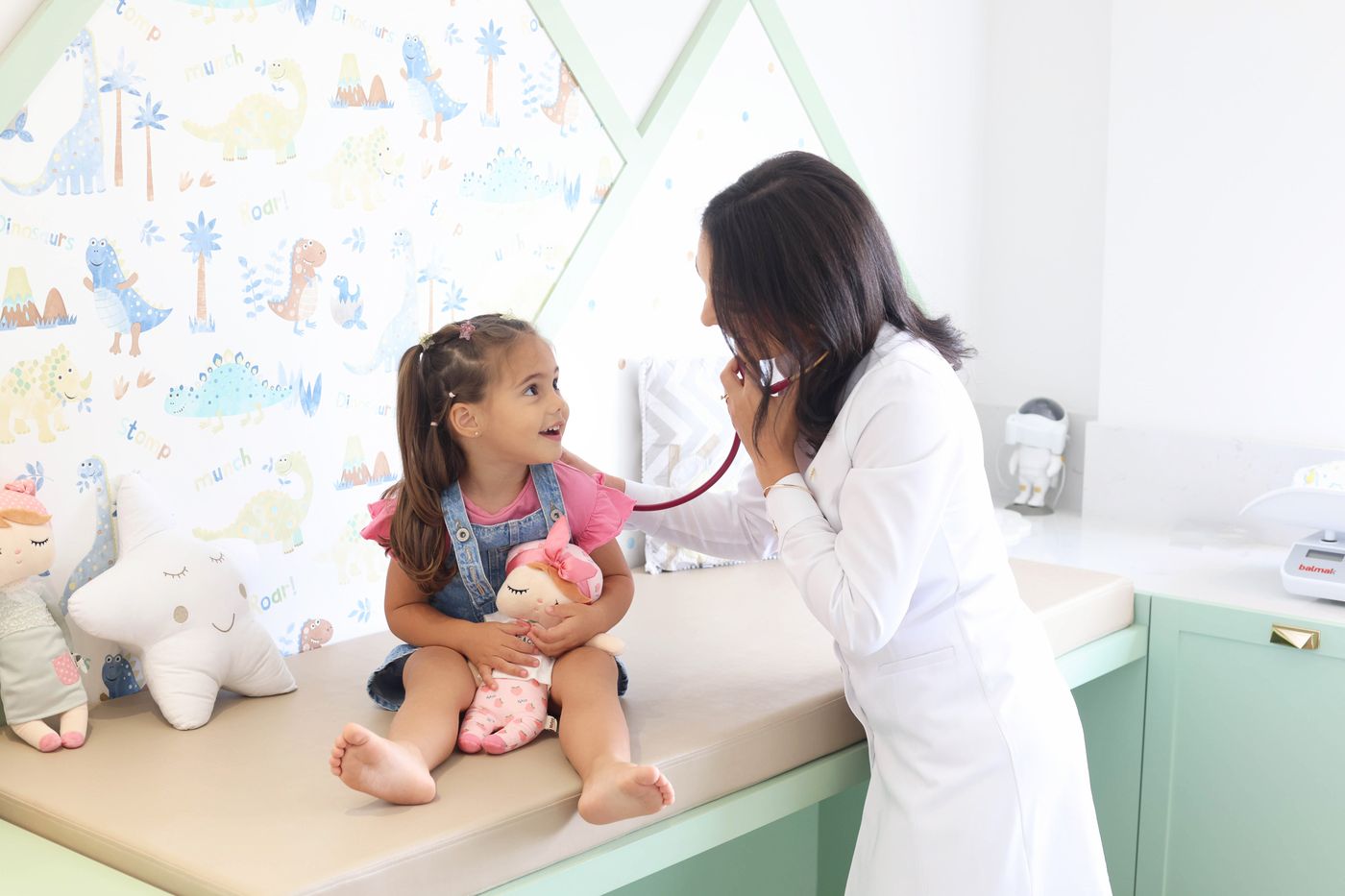 Consultório com maca e papel de parede infantil